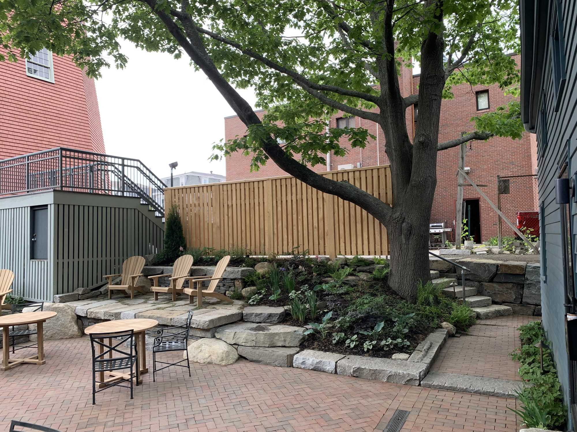 Stone planting bed and cedar fence beneath the courtyard's oak tree
