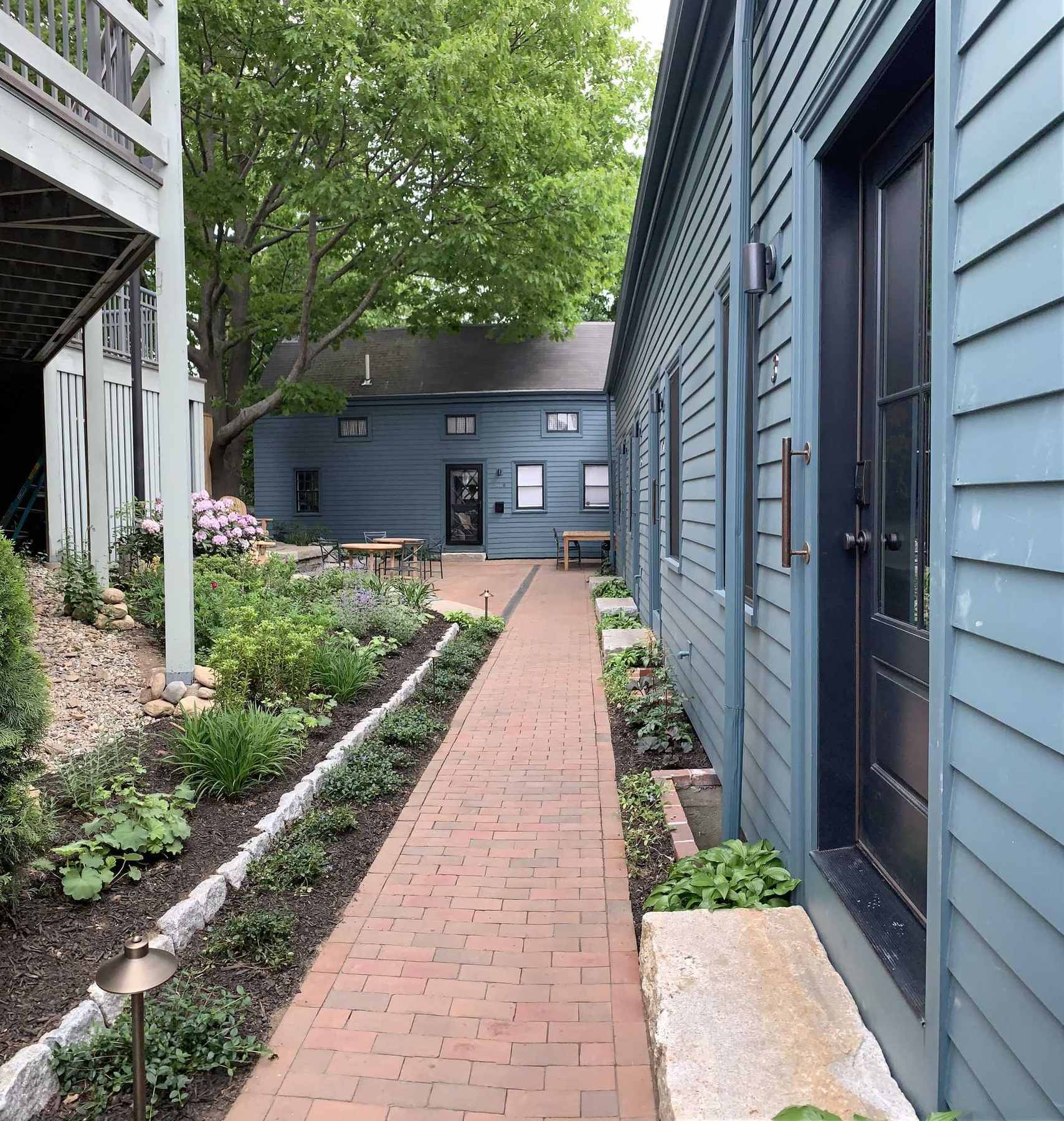 Brick walkway lined with garden plantings between buildings