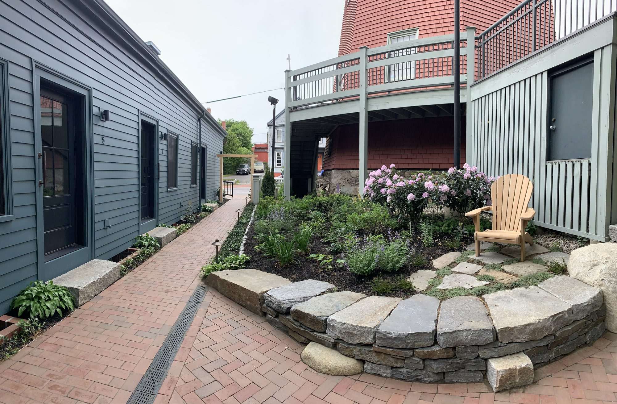 Stone retaining wall with seasonal plantings and brick paving