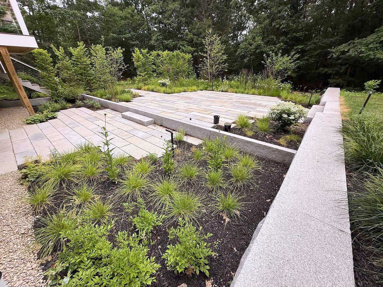 Back patio with granite pavers meeting a wildflower meadow