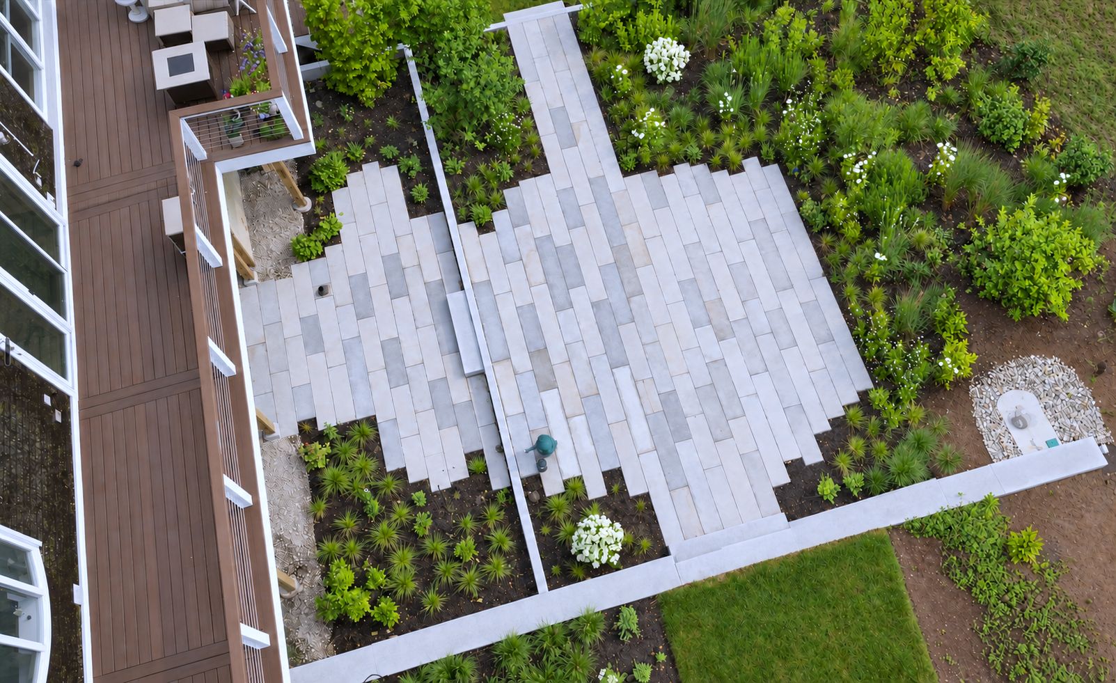 Aerial view of a granite plank patio with plantings beside a deck