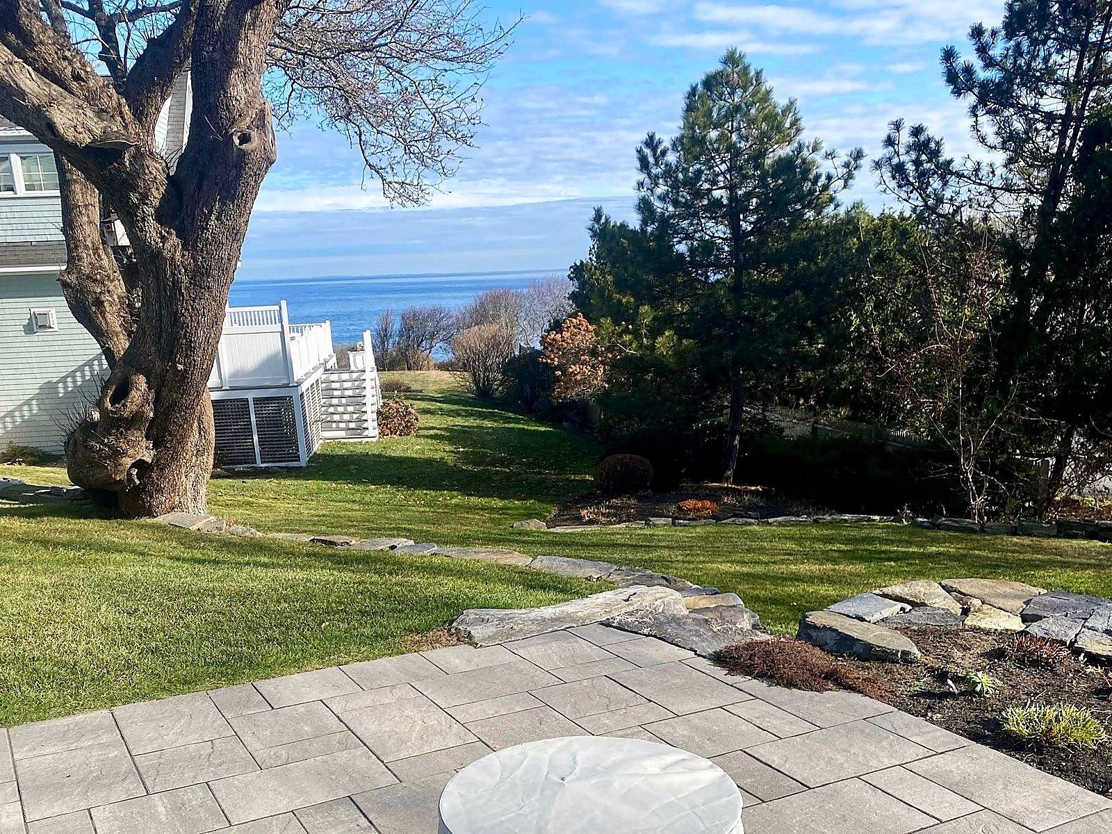 Paver patio and stone edge looking over the lawn to the ocean
