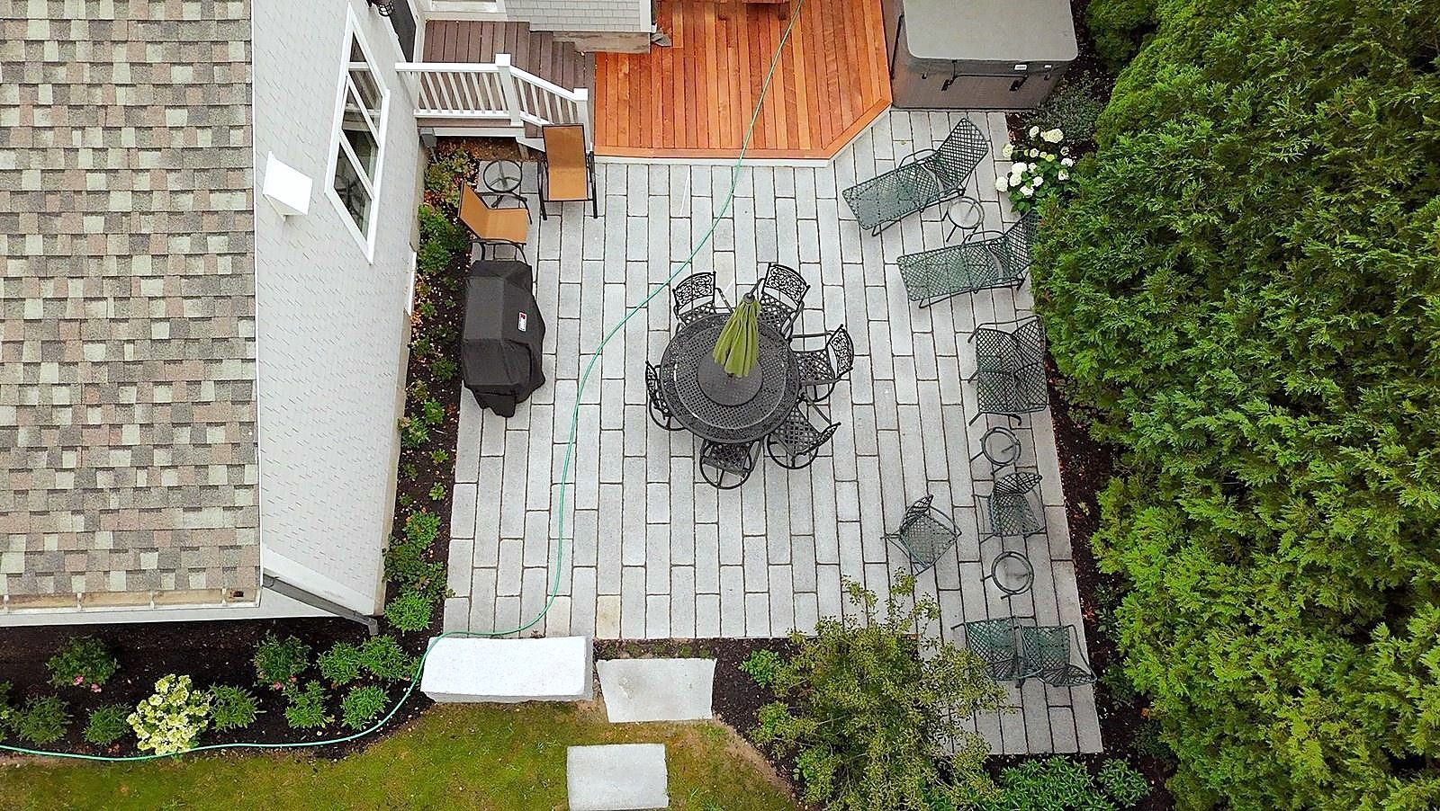 Aerial view of a private backyard patio with hot tub and gardens