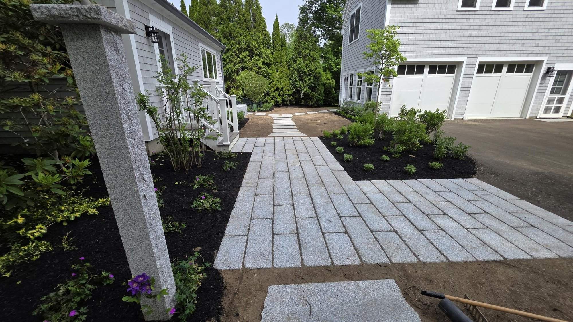 Granite walkway running toward the garage, with mulch beds on both sides and entry steps in the foreground