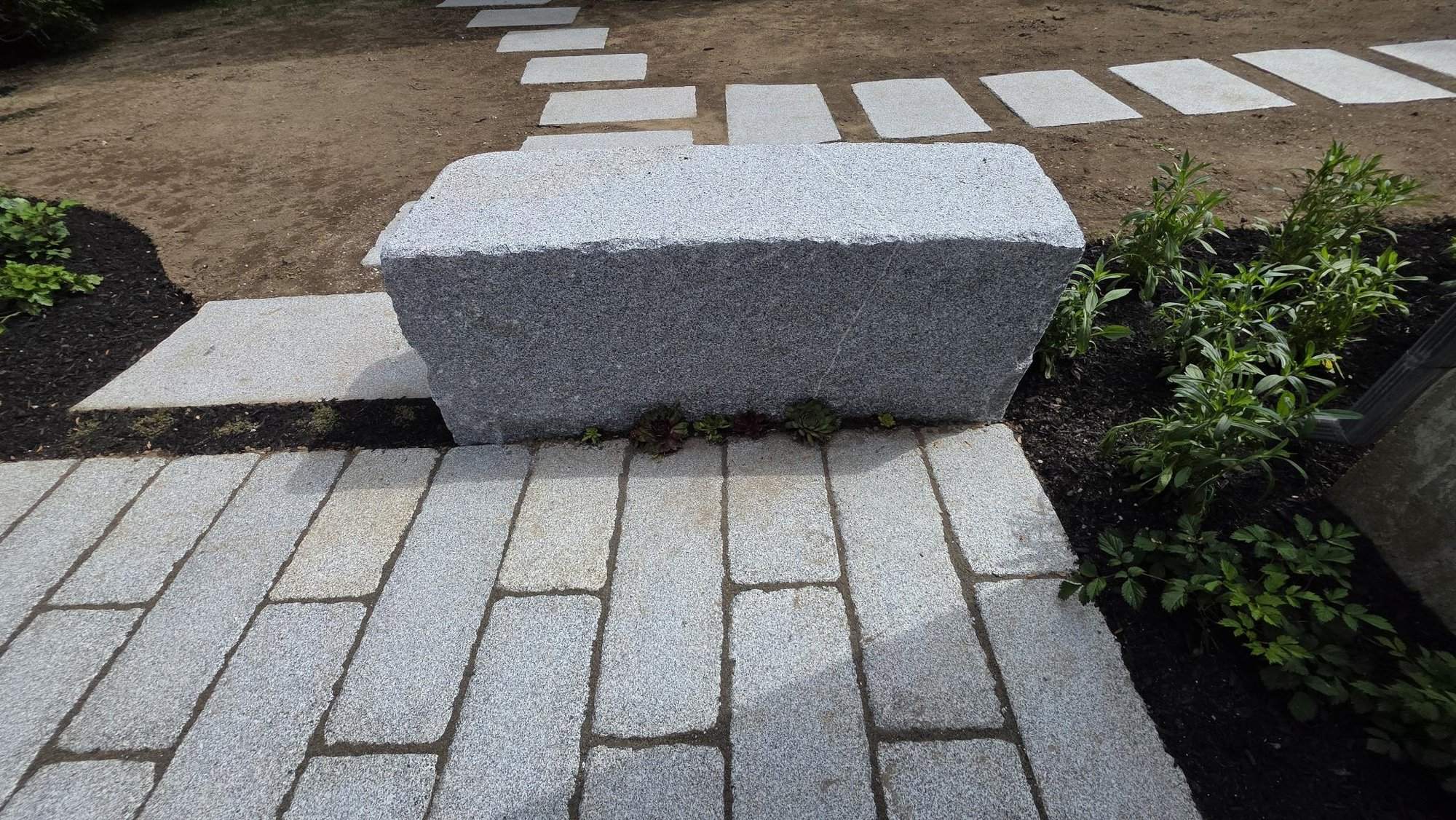 Close-up of a large cut granite block at the top of the stepping stone path