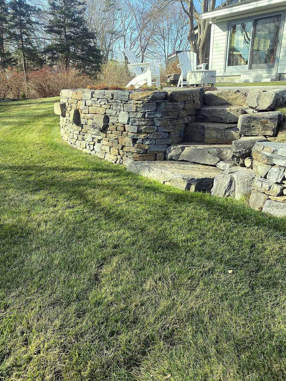 Stepped fieldstone retaining wall with granite steps on a lawn