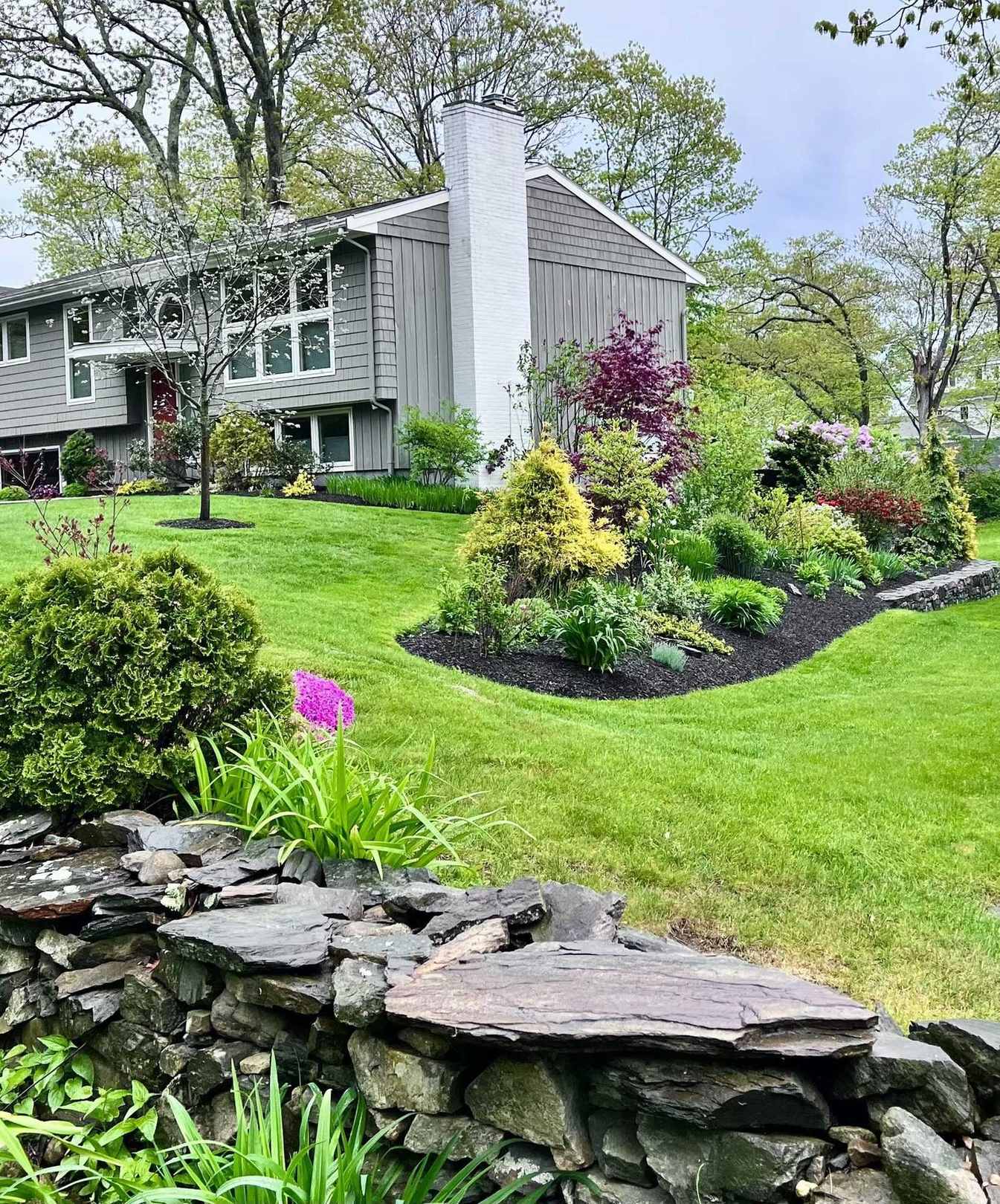 Front yard stone wall and garden bed with the house beyond