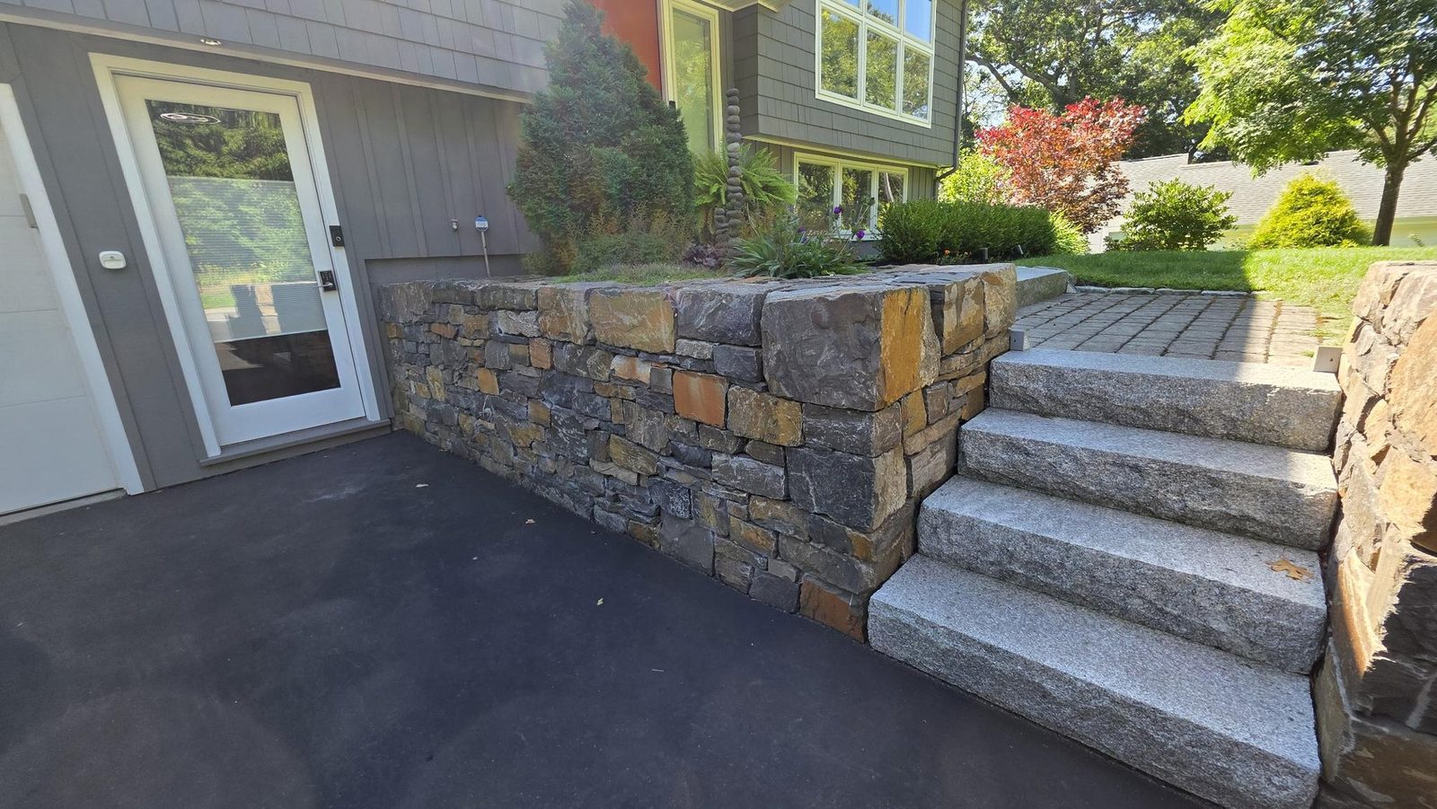Fieldstone retaining wall and granite steps beside the driveway