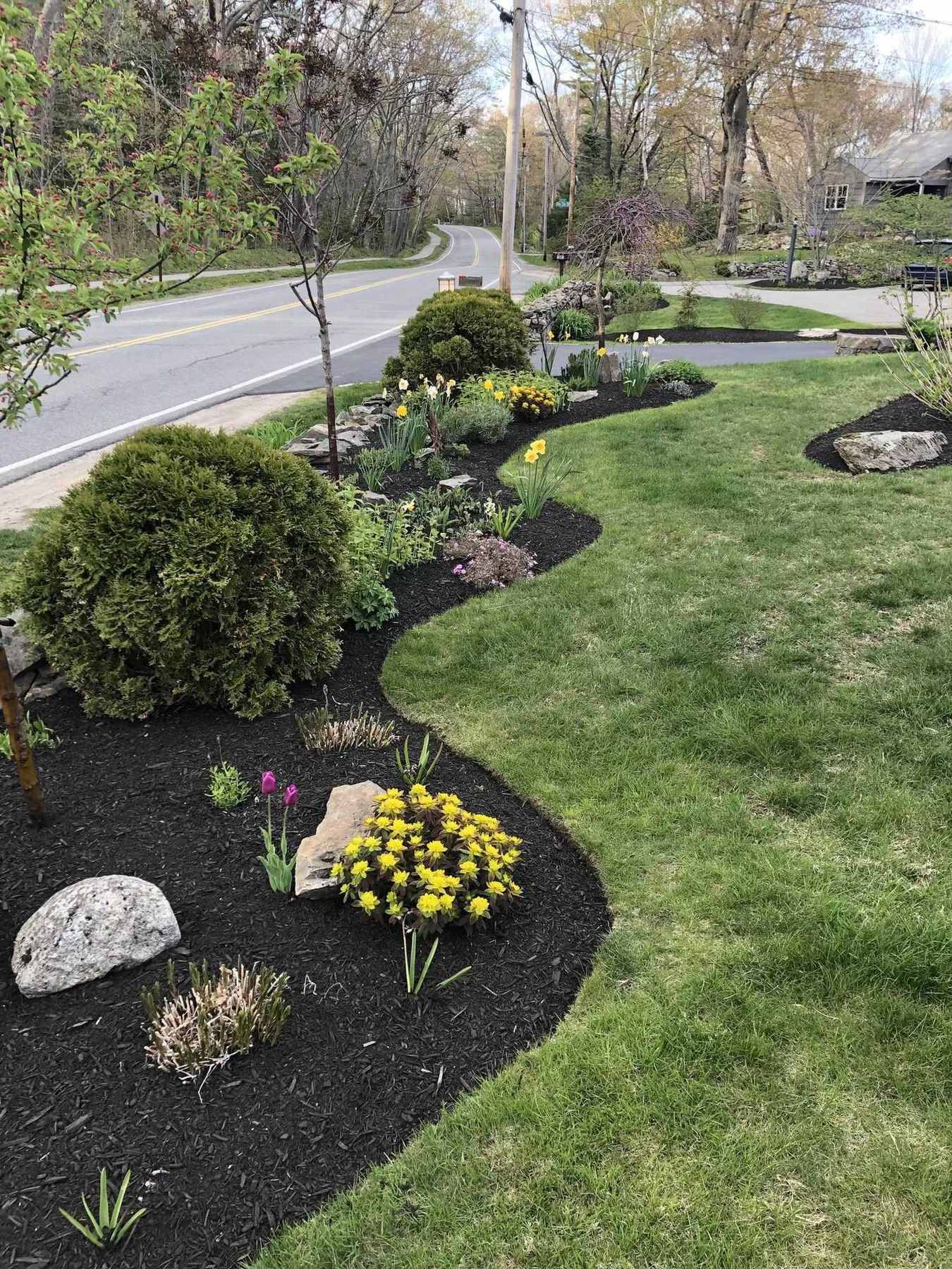 Curved garden bed along the road with stone edging