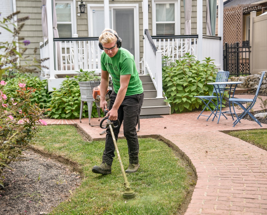 hero-gallery-02 Man weed wacking a customers grass next to a sidewalk with the house in the background.